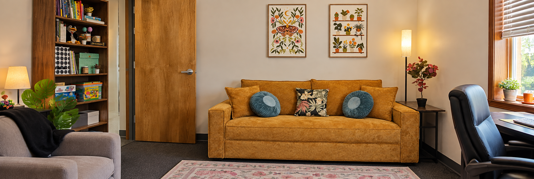 Welcoming therapy office with a mustard sofa, teal cushions, and botanical artwork